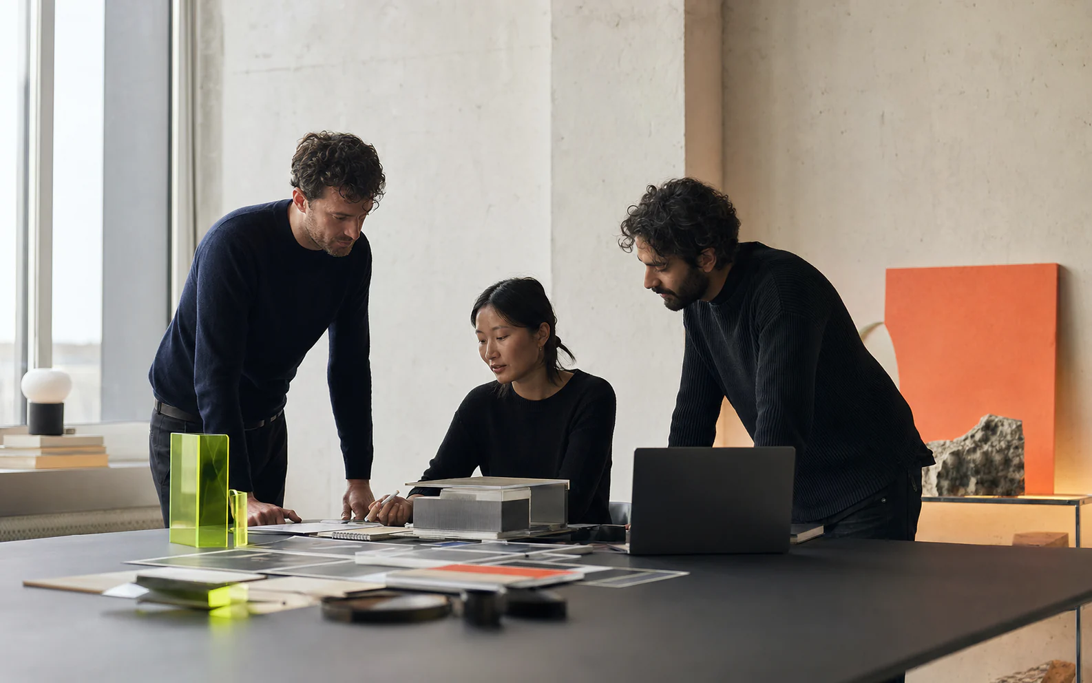 Three fictional creative technologists collaborating around a studio table